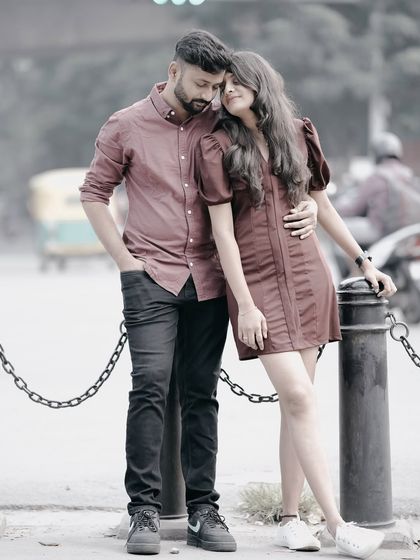 A romantic embrace on a city street, with the couple standing by a chain-linked bollard, creating a moody and intimate urban portrait.