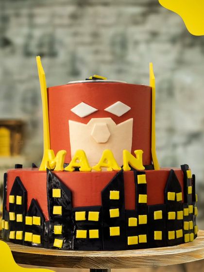 A heroic two-tier Batman cake, featuring the iconic Bat-Signal against a Gotham city skyline. This dark and cool design is perfect for a fan of the Caped Crusader.