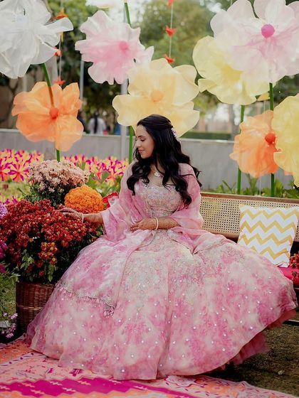 The bride posing in the garden Mehendi setting, her floral lehenga perfectly complementing the decor.
