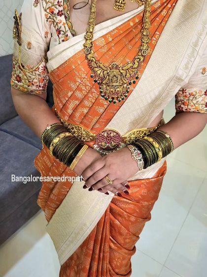 This image captures the art of draping a heavy silk bridal saree. The pleats are crafted to be 'fluffy' and full, giving the saree a grand appearance suitable for a wedding ceremony.