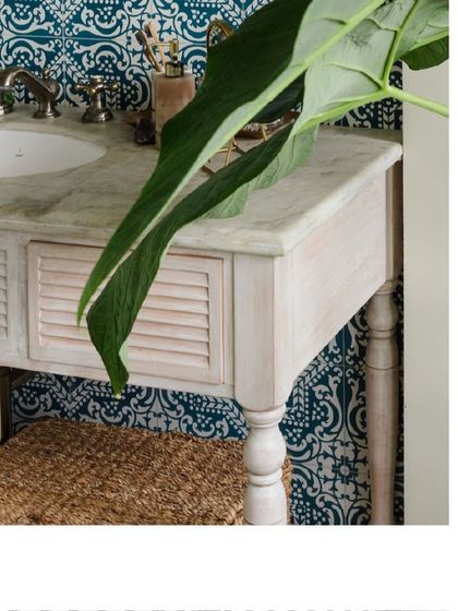 The bathroom vanity combines a marble top with a distressed white finish and louvered doors, creating a relaxed, coastal feel.