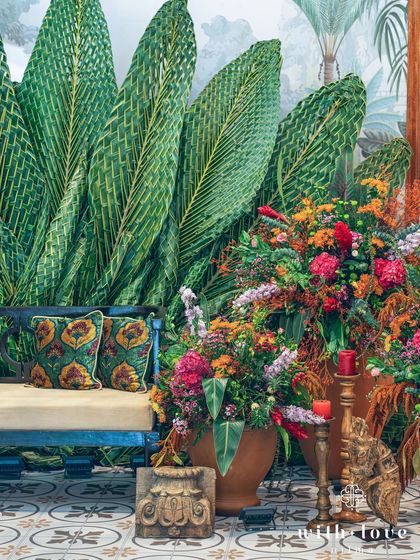 A full view of the Pellikuthuru ceremony setup, with the bride-to-be seated on a bench against the magnificent woven coconut leaf backdrop.