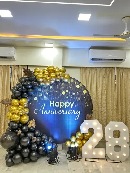 Another angle of the 28th anniversary home decoration. The lighting highlights the sparkling backdrop and the elegant black and gold balloon arrangement.