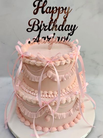 Embracing the trendy bow cake style, this two-tiered pink creation features vintage-style piping and delicate ribbons. It's a perfect blend of girly charm and elegant design for a special birthday.