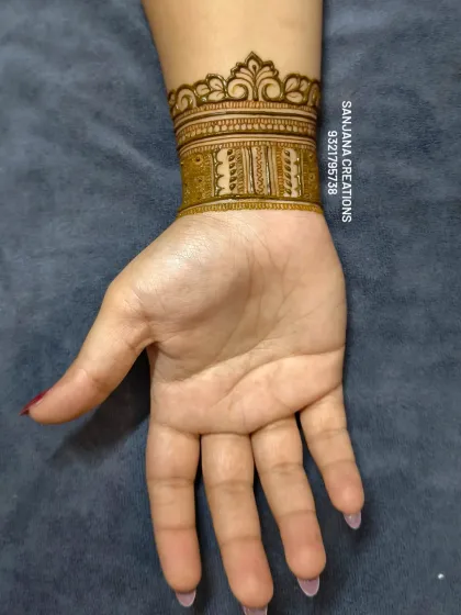 A close-up of the elegant wristband or 'hathphool' part of the bridal design, featuring clean lines and traditional motifs.