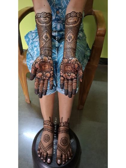 A complete bridal look showing the intricate mehendi on both the hands and feet. The designs are coordinated to create a cohesive and beautiful look for the bride's special day.