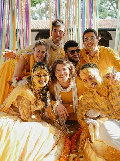 The couple and their friends pose for a group photo, all covered in turmeric, capturing the messy, joyful spirit of the Haldi.