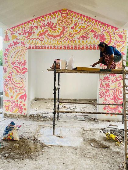 Perched on the scaffolding, I'm filling in the upper sections of the 'Baba's Garden' mural. Working on a large scale like this is physically demanding but so rewarding when you see the art transform the entire structure.