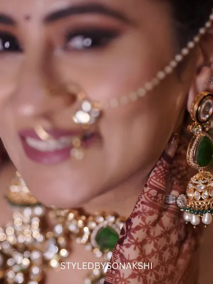 The beauty is in the details. This close-up shot showcases the intricate bridal jewellery we selected for Surbhi, featuring green stones that add a pop of color against her skin and the rich tones of her wedding outfit.