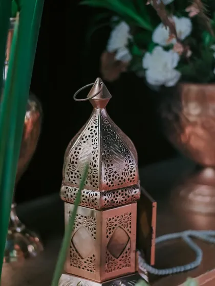 An ornate, perforated metal lantern adds a touch of Moroccan-inspired elegance and warm, patterned light to a decor vignette.