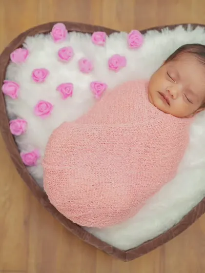 For my posed newborn sessions, I use a variety of props like this heart-shaped basket. I ensure your baby is safely and comfortably swaddled, creating a peaceful and adorable portrait.