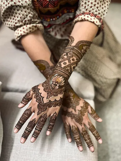 An elegant and flowing design that combines traditional paisley shapes with delicate floral elements, creating a soft yet intricate look on the hands and arms.