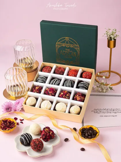 A box of assorted artisanal truffles for Diwali. The elegant green packaging and gold lettering are highlighted by the surrounding props, creating a luxurious feel.