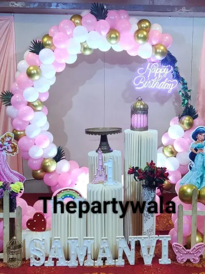 A classic princess theme with a pink and gold balloon arch and cutouts of Princess Jasmine and Aurora. The setup is placed on a red carpet for an extra royal feel.