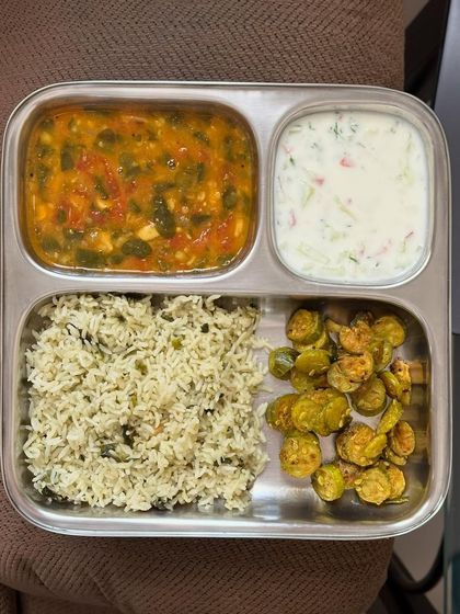 This plate features dill-flavored rice with dal, sautéed ivy gourd, and a refreshing raita.