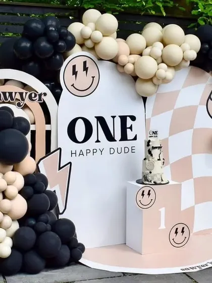 The full setup for the "One Happy Dude" birthday party, showing the coordinated backdrop, cake stand, and balloon decorations.
