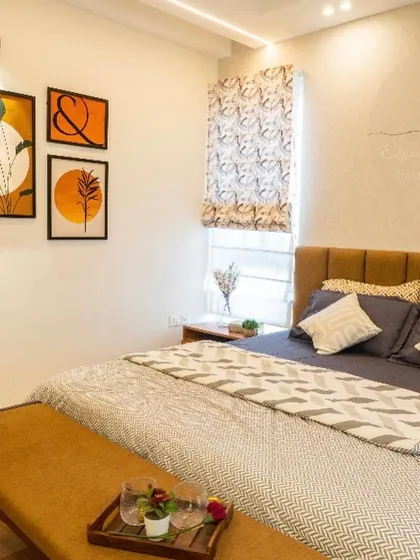 This master bedroom features warm, earthy tones and modern art. The combination of a comfortable upholstered bed, a sleek bench, and patterned blinds creates a stylish and personal retreat.