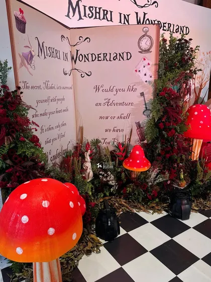 A close-up of the storybook entrance, surrounded by giant mushrooms and lush red foliage, inviting guests into a magical world.