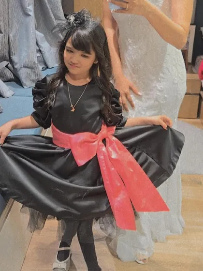 We love creating magical moments for our youngest clients. Here is our lovely client Ayana in a custom black party dress with a vibrant pink satin bow, designed to be as fun and special as she is.