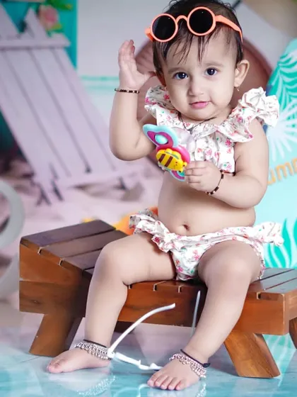 This little fashionista tries on her sunglasses, adding a cool and playful vibe to her beach photos.