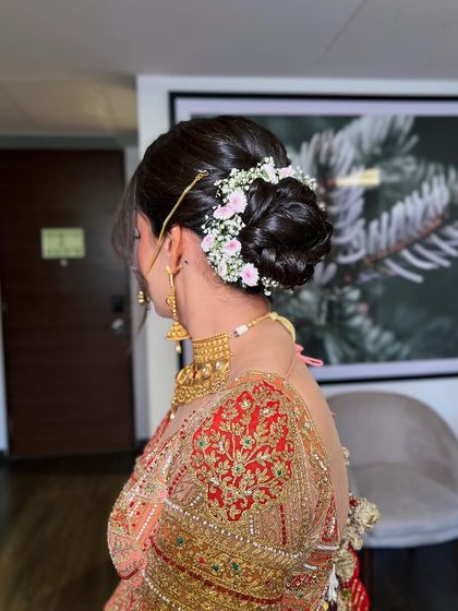 A classic bridal bun for a Rimple and Harpreet bride, decorated with delicate pink and white flowers.