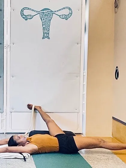 Summer practice often calls for long, cooling holds in supported poses. Here, Supta Padangusthasana (Reclining Hand-to-Big-Toe Pose) with a belt and bolster helps to release the hamstrings and hips without generating excess heat, calming the entire system.