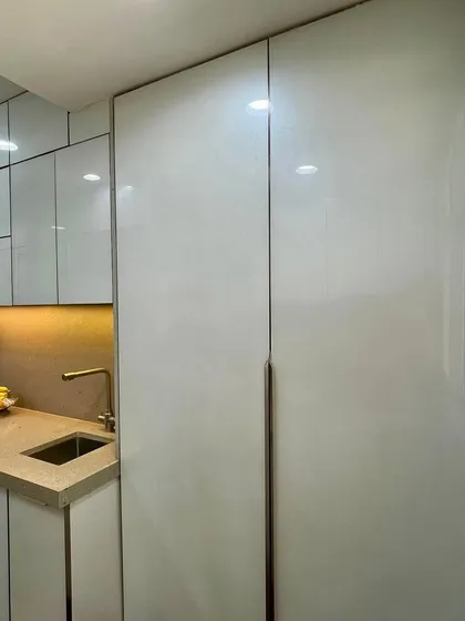 A tall, handleless cabinet in a white laminate finish, providing floor-to-ceiling storage.