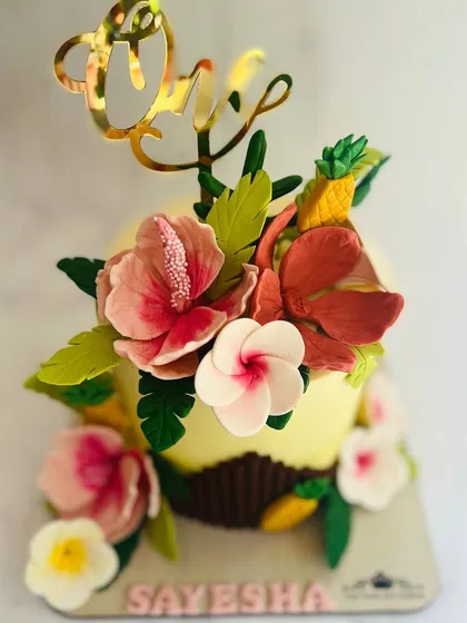 A beautiful tropical-themed smash cake for a first birthday. It's decorated with handcrafted, edible hibiscus flowers and pineapples.