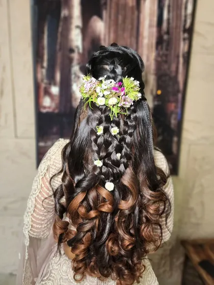 This intricate braided hairstyle is a true work of art, featuring multiple braids woven together and adorned with fresh flowers. It's a unique and stunning choice for a mehendi or sangeet ceremony.
