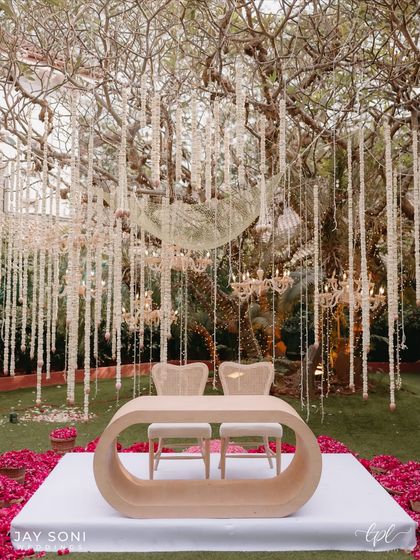 A wider view of the dreamy ceremony setting, where the modern couple seating is surrounded by a field of pink petals, creating a scene where every detail feels like a dream come true.