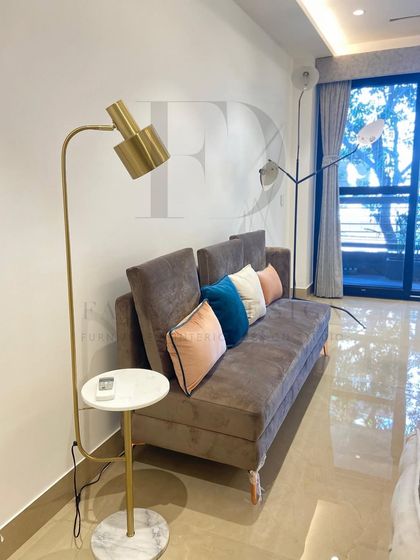 This sofa bed in a rich brown fabric is a perfect example of functional luxury. It's paired with a modern floor lamp that includes an integrated marble-topped side table, ideal for compact living spaces.