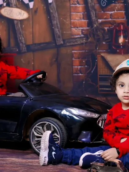Two brothers posing with a toy car in our cool garage-themed studio setup.