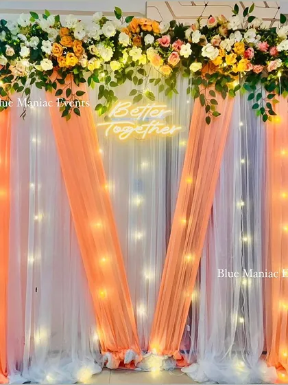 A full view of the peach and white 'Better Together' backdrop, showing the delicate draping and the warm glow of the fairy lights.