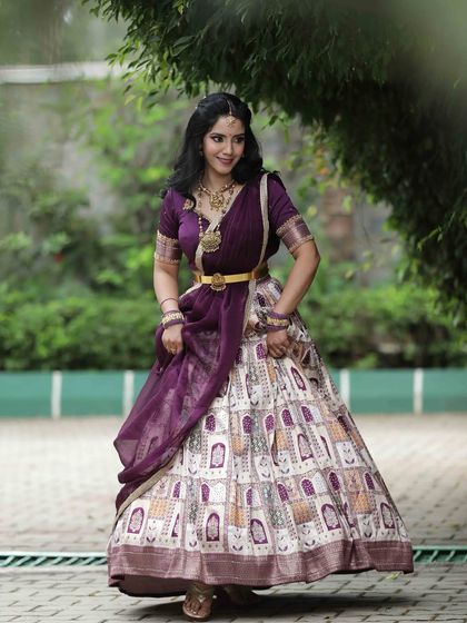 A full-length shot of a model in a purple and white lehenga, capturing a moment of graceful movement.