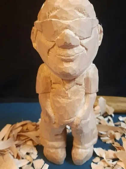 This is what a figurine looks like after the carving is complete but before any paint has been applied. You can see the raw, textured wood and the pile of wood shavings that are a happy byproduct of my work.