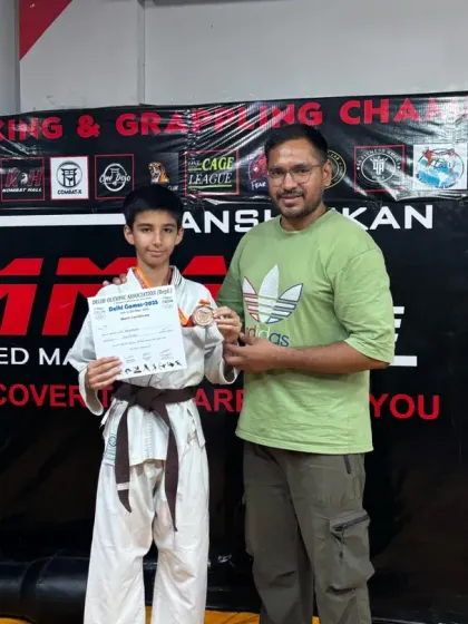A young student in his karate gi proudly displays his medal and certificate. We believe in recognizing and celebrating the hard work of every student.