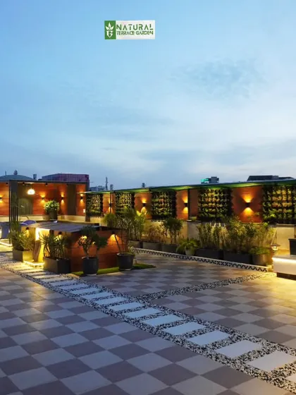 A panoramic view of a large terrace in Palam Vihar, featuring a long bench with integrated lighting, vertical gardens, and a bar area.