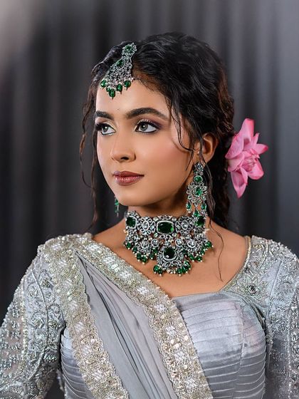 A three-quarter portrait of the grey saree and emerald jewelry look.