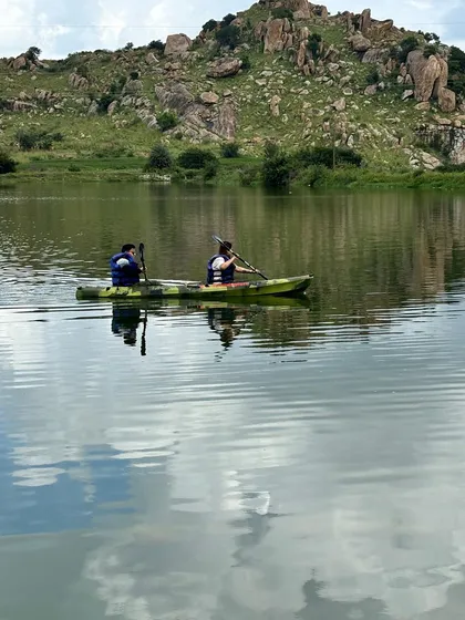 A beautiful reflection of the clouds on the water as two people kayak.
