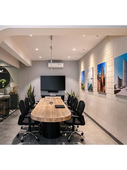 The conference room is bright and subtle, with a custom-built table that echoes the language of the ceiling fins. The wall is clad in light-colored clay tiles, adding texture and maintaining a light, airy feel.