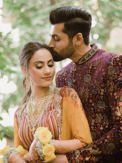 A romantic portrait of Bhavita and Niel from their Haldi day, the groom's gentle kiss a sweet promise.