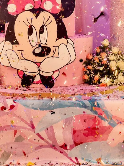 A close-up of a Minnie Mouse-themed birthday cake, surrounded by a shower of confetti. We ensure every detail, including the cake presentation, fits the party's theme.