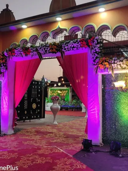 I design grand entrances to welcome your guests. This entranceway for a wedding features a floral arch, elegant pink draping, and green panels with accent lighting to set the tone for the celebration.