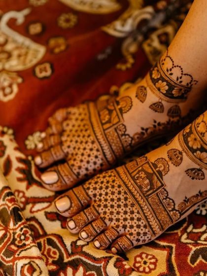A candid shot of a bride's feet, adorned with beautiful mehndi. The design features traditional motifs that complement her bridal attire.