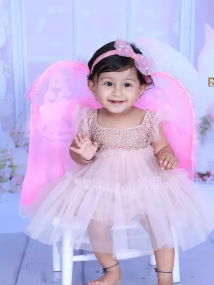 A smiling fairy princess waves to the camera, her pink wings glowing in the soft light. This whimsical setup is perfect for capturing your child's magical spirit.