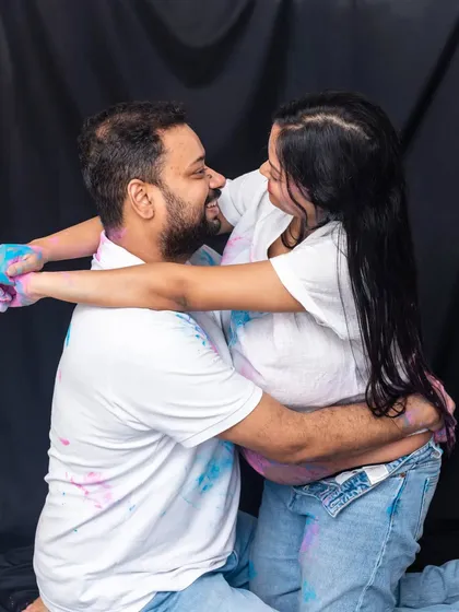 The aftermath of a paint-filled gender reveal. This candid shot captures the laughter and love between the couple, covered in blue and pink powder.