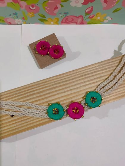 This boho-style choker is made with embroidered flower motifs and a braided cord. It's a delicate yet eye-catching piece that comes with matching stud earrings.