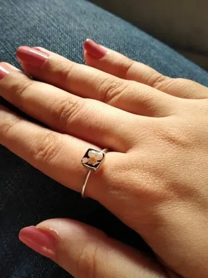 This minimalist ring features a tiny 'touch-me-not' flower preserved in a square silver-toned setting. It's a delicate and pretty piece for everyday wear.