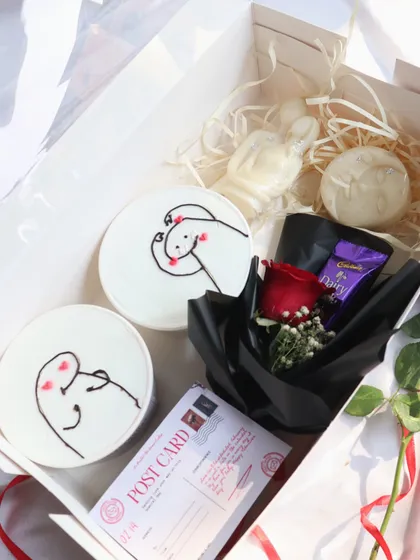 "The Love Story" hamper, beautifully arranged with dessert tubs, candles, a postcard, and a rose.