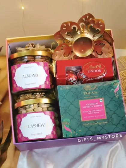 An overhead view of our premium multi-colored hamper, showing the arrangement of dry fruit jars, Lindt chocolates, saffron kahwa tea, and a lotus diya.